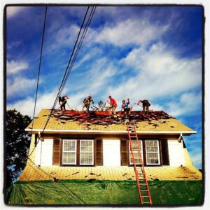people repainting a roof red